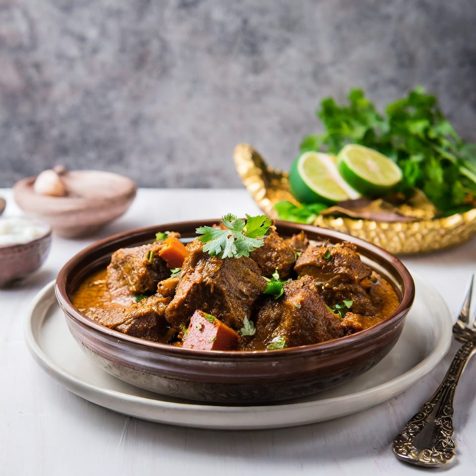 A bowl of rich Indian lamb curry with cilantro and lime, from Curry Nights.