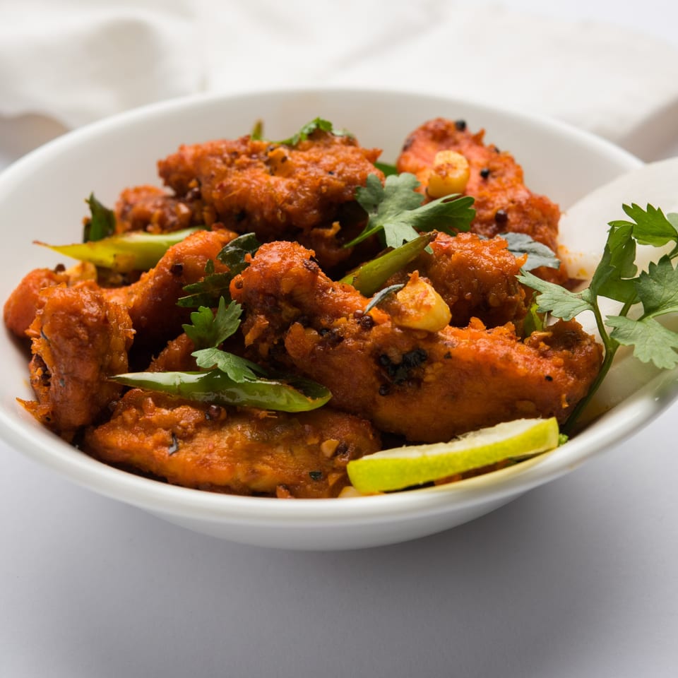 Curry Nights' Chicken 65, a spicy Indian fried chicken dish, garnished with cilantro and lime.